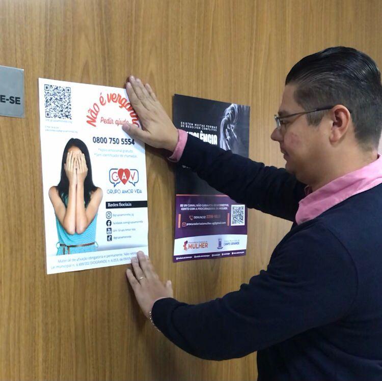 Vereador Otávio Trad fixa cartaz de apoio emocional do Grupo Amor Vida na Câmara Municipal.